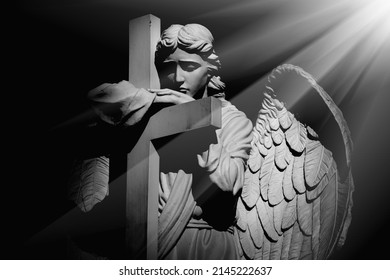 Death Concept. Silhouette Of Angel With Cross In Rays Of Light. Ancient Statue. 