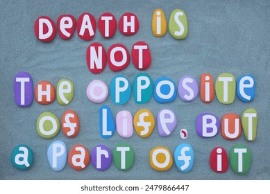 Death is not the opposite of life, but a part of it, life quote composed with hand painted multi colored stone letters over green sand - Powered by Shutterstock