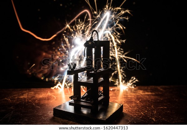 Death penalty electric chair miniature on\
dark. Creative artwork decoration. Image of an electric chair scale\
model on a dark\
backgorund