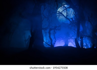 Death with a scythe in the dark misty forest. Woman horror ghost holding reaper in forest, halloween concept. Creative artwork table decorations in selective focus