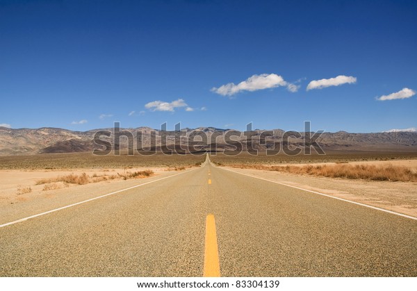 Death Valley road straight  across the desert to\
the mountains in the\
distance
