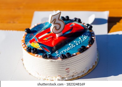 DEBINA, POLAND - Aug 01, 2020: Brithday Cake With Lightning McQueen Theme And A Three Shaped Candle On A Table.