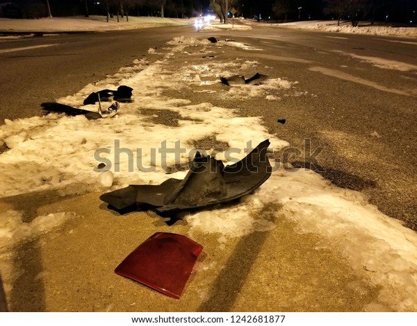 Debris\
on snow on the road after a car accident at\
night.