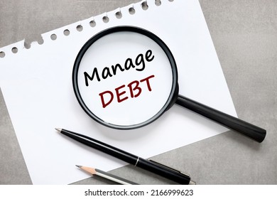 Debt Management Plan On A Gray Table. Magnifying Glass Text