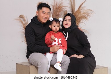 Dec, 2019 - Pekanbaru, Indonesia: 
Happy Family Studio Photoshoot In Light Grey Background, Use Sweater. Photo Concept In Black, Grey And Brick Red Dress Code, Sit On Brown Box And Dried Leaves.