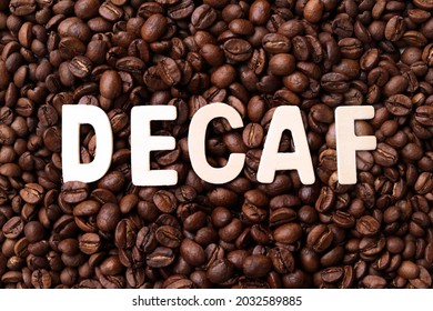 Decaf word on roasted coffee beans background. Concept of decaffeinated coffee or low caffeine coffee.