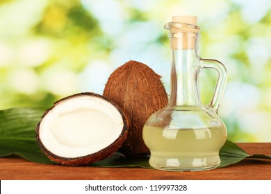 decanter with coconut oil and coconuts on green background