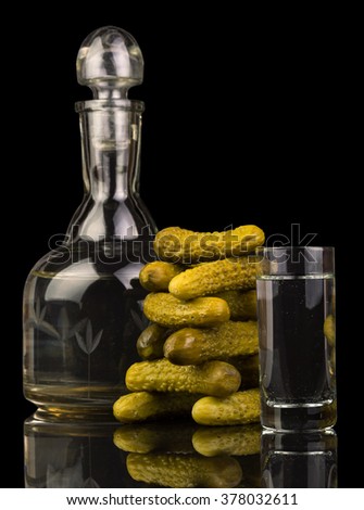 Decanter and glass with vodka and pickled cucumbers isolated on a black background