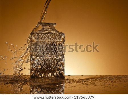 Decanter  on a gold background with splash of liquid