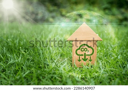 Decarbonization of Real Estate. Lower CO2 emissions and reduce carbon. Miniature wooden house model and white tag with co2 neutral markers on green grass. conservation house concept environmentally.  