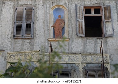 Decayed building facade with weathered statue in niche alcove arched recess. Neoclassical architecture, Athens Greece.