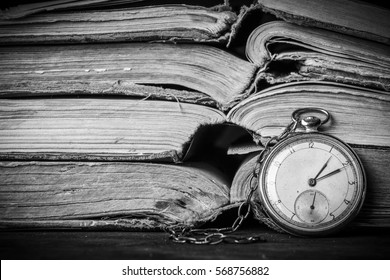 Decaying clock on the background of old shabby wise books. Black and White photograph - Shutterstock ID 568756882