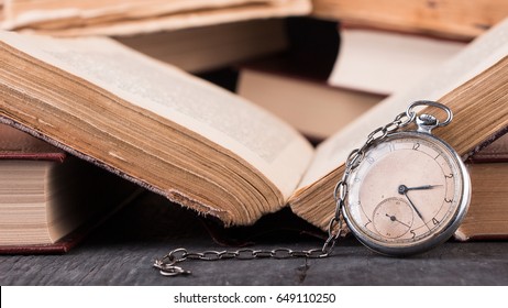 Decaying clock on the background of old shabby wise books. - Shutterstock ID 649110250