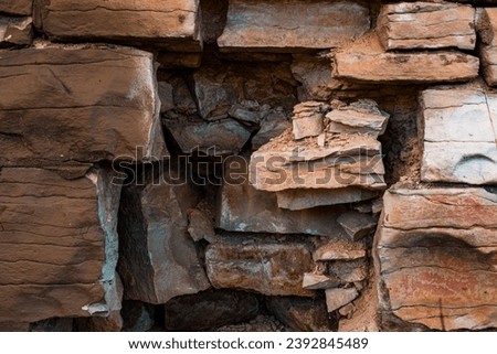 Decaying stone wall with eroded bricks and stones, showcasing a variety of textures and colors