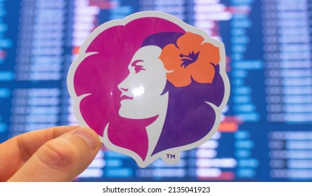 December 11, 2021, Honolulu, USA. The emblem of Hawaiian Airlines against the background of an electronic scoreboard with flight schedules at the international airport.