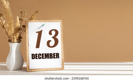 december 13. 13th day of month, calendar date.White vase with dead wood next to cork board with numbers. White-beige background with striped shadow. Concept of day of year, time planner, winter month.