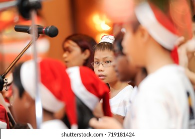 December 2016,Malaysia. Selective Focus On A Group Of Kids Choir Wearing Christmas Santa Claus Hat At Christmas Dinner Event With Artificial Grain Effects.Christmas Celebration.