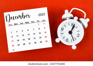 December 2023 Monthly calendar year with alarm clock on red background. - Shutterstock ID 2337755685
