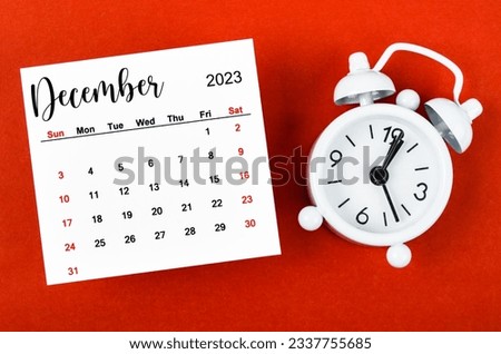 December 2023 Monthly calendar year with alarm clock on red background.