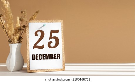 december 25. 25th day of month, calendar date.White vase with dead wood next to cork board with numbers. White-beige background with striped shadow. Concept of day of year, time planner, winter month.