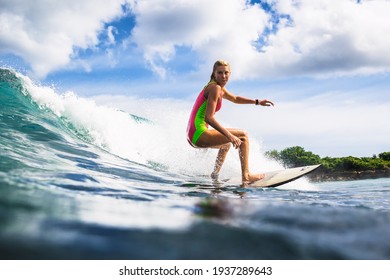 December 30, 2020. Bali, Indonesia. Woman in tropical ocean during surfing. Surfer girl on surfboard. 