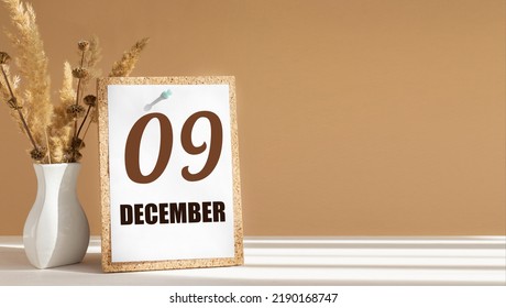 december 9. 9th day of month, calendar date.White vase with dead wood next to cork board with numbers. White-beige background with striped shadow. Concept of day of year, time planner, winter month.