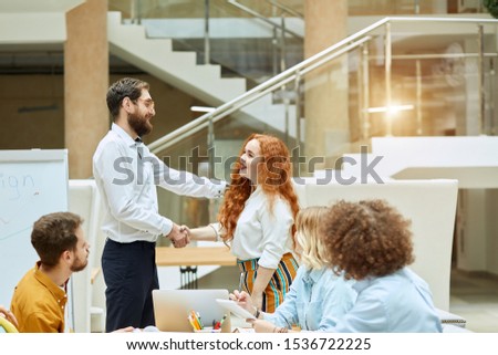 Decent, impressive middle aged manager friendly congratulates, young pretty female worker with successful job position, office work concept