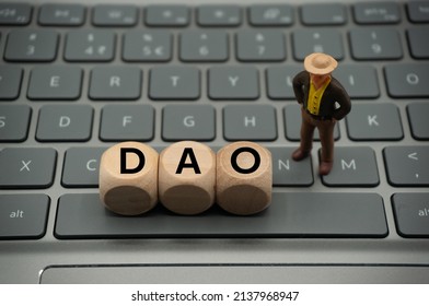Decentralized Autonomous Organizations (DAO) are internet communities that are run on blockchain technology and use code to establish rules and make decisions.word is written on dice, keyboard.