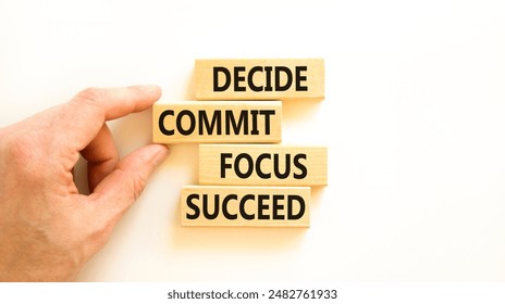 Decide commit focus succeed symbol. Concept word Decide Commit Focus Succeed on wooden block. Beautiful white background. Businessman hand. Business decide commit focus succeed concept. Copy space.