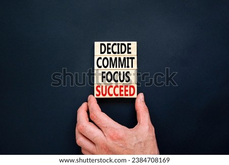 Decide commit focus succeed symbol. Concept word Decide Commit Focus Succeed on wooden block. Beautiful black background. Businessman hand. Business decide commit focus succeed concept. Copy space.