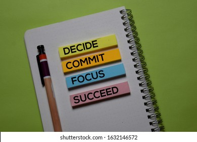 Decide. Commit. Focus. Succeed write on a sticky note isolated on office desk.