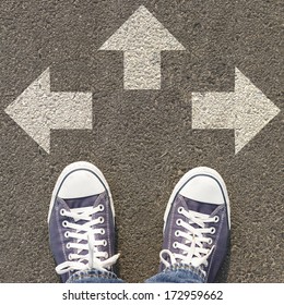 Deciding To Choose A Path In Real Life, With Many Paths To Choose From. Sneakers Standing On The Road With Three Directional Arrows, Concepts Of Making, Decisions, Crossroads, Choice