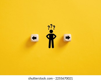 Decision making and choosing the right path. Confusion about deciding which direction to go. Stickman with question marks standing in between the wooden cubes with arrow symbols. - Shutterstock ID 2255670021