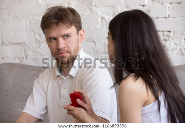 Decisive\
girlfriend making marriage proposal to frustrated boyfriend,\
presenting engagement ring, feminist woman asking surprised puzzled\
lover to marry, setting family. Feminism\
concept