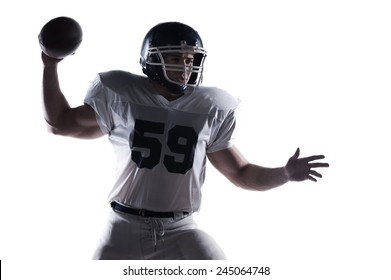 Decisive Shot.  American Football Player Throwing Ball Standing Against White Background 