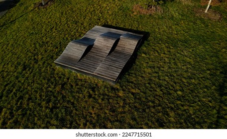 deck chair composed of three waves which are made of wood and board. large seating elements in a landscape park. furniture for tenagers, aerial view, green, three parts, drone point of view, beach