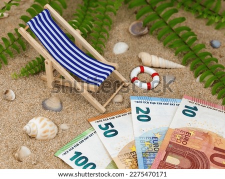 deck chair with euro banknotes in the sand with sea shells and tropical background, concept of saving money for a holiday trip or high vacation expenses