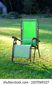 Deck Chair In A Green Grass At Home Backyard On A Hot Summer Day