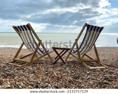 Deck chairs on seaside beach of Hastings East Sussex Uk, sea sky and ocean behind 