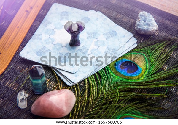 Deck with divination homemade\
Angel cards on black table, surrounded with semi precious stones\
crystals. Selective focus on amethyst crystal angel\
figurine.