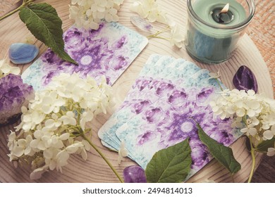 Deck with homemade divination Angel cards on wood table with hydrangea flower for decoration. Home indoors candle burning.