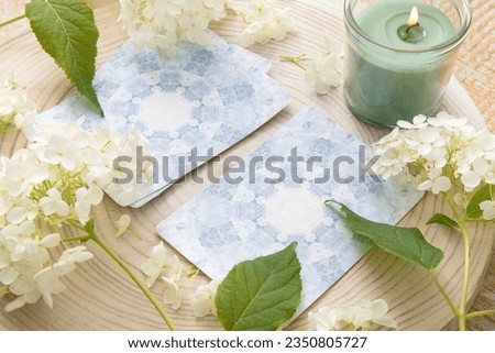 Deck with homemade divination Angel cards on wood table with hydrangea flower for decoration. Home indoors candle burning.