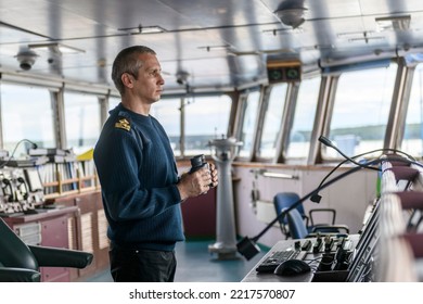 Deck officer with binoculars on navigational bridge. Seaman on board of vessel. Commercial shipping. Cargo ship. - Shutterstock ID 2217570807