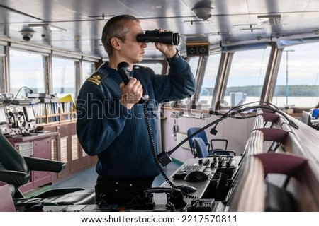 Deck officer with binoculars on navigational bridge. Seaman on board of vessel. Commercial shipping. Cargo ship. Foto stock © 