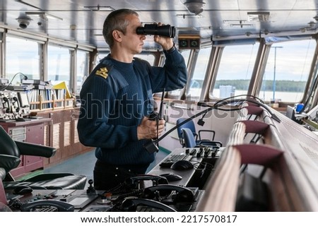 Deck officer with binoculars on navigational bridge. Seaman on board of vessel. Commercial shipping. Cargo ship. Foto stock © 