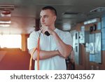 Deck officer on the bridge during navigational watch at sea. Offshore technician. Seafarer. Seaman. Navigator. A man in the wheelhouse with a radio station. Chief mate on board the merchant ship.