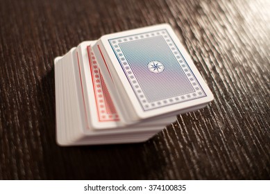 Deck of red and blue stacked playing cards on a wooden table with focus to the top card and copy space