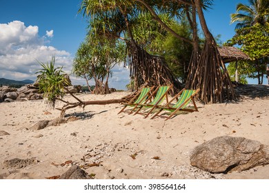 Deckchairs on a beautiful sandy beach with colorful nature on background. Vacation concept. 