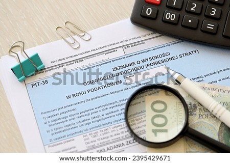 Declaration of the amount of earned income or incurred loss, PIT-38 tax forms on accountant table with pen and polish zloty money bills close up