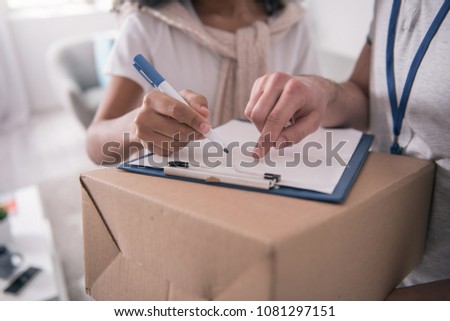 Declaration of conformity. Close up of a delivery declarations being in hands of a smart professional courier